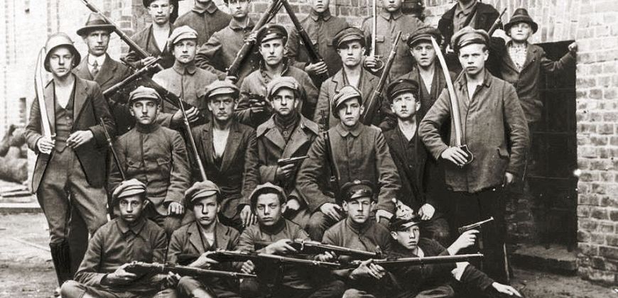 Grupa powstańców uzbrojonych w karabiny i szable oraz pistolety Parabellum P-08 (lhttps://www.szukajwarchiwach.gov.pl)